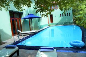 a swimming pool with a blue umbrella and chairs at Tropical Retreat in Unawatuna