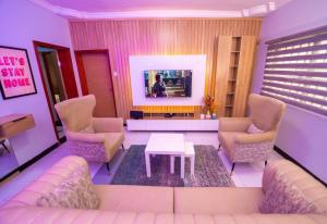 sala de estar con sofá, sillas y TV en Palm Heights Apartments - Omole Phase 1, Ikeja en Ikeja