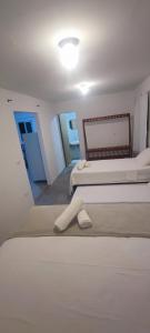 a white bedroom with two beds and a mirror at Pousada Sunshine - Praia do Patacho in Pôrto de Pedras