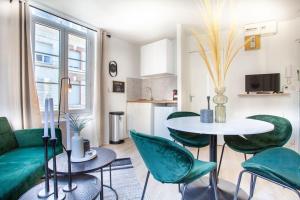 uma sala de estar com uma mesa e cadeiras verdes em La Suite : studio Hypercentre - Cathédral em Amiens
