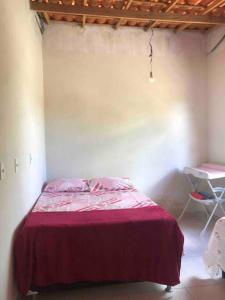 ein Schlafzimmer mit einem Bett mit einer roten Decke in der Unterkunft Casa no Campo in Senhor do Bonfim