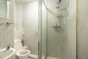 a white bathroom with a shower and a toilet at Cozy studio for your stay in New Southgate