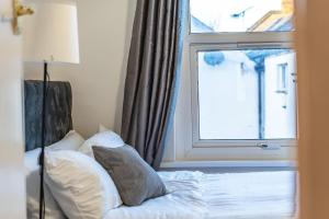 ein Bett mit Kissen und ein Fenster in einem Zimmer in der Unterkunft Cozy studio for your stay in New Southgate