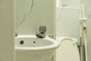 Baño blanco con lavabo y aseo en Cozy studio for your stay en New Southgate