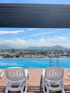 zwei Stühle auf einer Terrasse mit Blick auf das Wasser in der Unterkunft The Horizon Ipoh By Iconique Espace in Ipoh