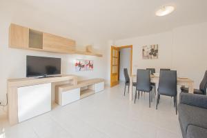 ein Wohnzimmer mit einem Tisch mit Stühlen und einem TV in der Unterkunft Apartamento Zeus - PlusHolidays in Calpe