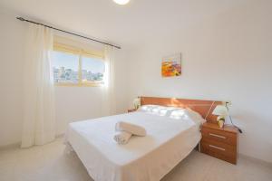 biała sypialnia z łóżkiem i oknem w obiekcie Apartamento Zeus - PlusHolidays w mieście Calpe +3 zdjęcia
