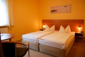 una habitación de hotel con una cama grande con sábanas blancas en Hotel Balneolum Superior, en Quedlinburg
