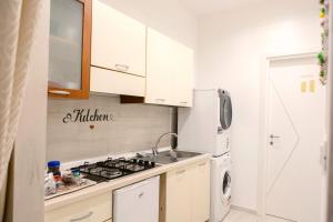 una cucina bianca con piano cottura e frigorifero di Flower's House 24 - Central Apartment - Molfetta a Molfetta