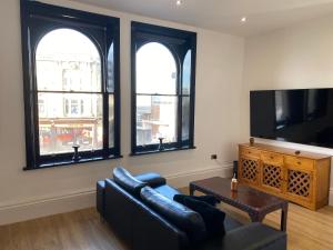 a living room with a couch and a tv and windows at No 10, St James Street, Burnley in Burnley