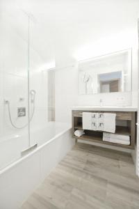 a white bathroom with a shower and a sink at Hotel Alpina Superior in Pettneu am Arlberg