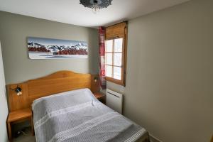 Schlafzimmer mit einem Bett und einem Fenster in der Unterkunft Le Col Roulé in Valloire