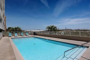 a swimming pool on a balcony with chairs and the beach at Gulf Dunes 305 Coastal Dream in Fort Walton Beach