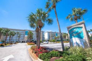 a building with palm trees in front of a street at Gulf Dunes 305 Coastal Dream in Fort Walton Beach
