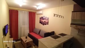 a living room with a red couch and a table at Sunshine II Apartment in Kragujevac