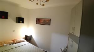 a bedroom with a bed and a light on the wall at Sunshine II Apartment in Kragujevac