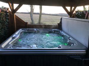un bain à remous avec des lumières vertes dans une arrière-cour dans l'établissement Couple’s Lodge With Hot Tub, à Lincolnshire
