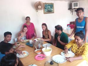 Un groupe de personnes assises autour d'une table et mangeant de la nourriture dans l'établissement UPPUVELI BEACH HOUSE, à Trincomalee