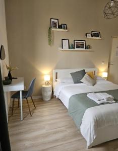 een slaapkamer met 2 bedden en een bureau en een tafel en stoel bij B&B GREEN Stazione Centrale in Reggio di Calabria