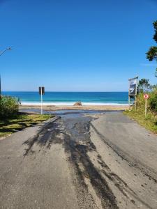 an empty road next to a beach with the ocean at Hospedagem Casa Maracujá in Trindade