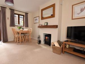 un salon avec une cheminée, une table et une télévision dans l'établissement 2 Bed in Moreton-In-Marsh 75870, à Whichford