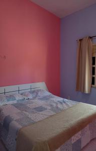 um quarto com uma cama com paredes cor-de-rosa e roxo em Chalé casa di Taipa em Lagoa Nova