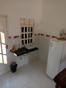 uma cozinha branca com um lavatório e um frigorífico em Chalé casa di Taipa em Lagoa Nova