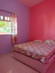 a bedroom with a bed with pink walls and a window at Chalé casa di Taipa in Lagoa Nova
