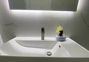 a white sink with a flower in a vase on it at Hotel Krial in Berat