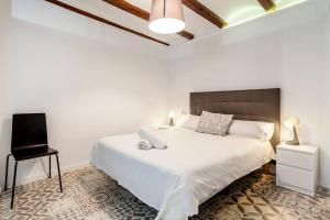 een slaapkamer met een wit bed en een zwarte stoel bij Exclusivo apt. en centro histórico · AC · Wifi in Valencia