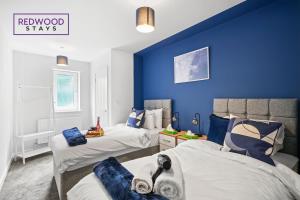 1 dormitorio con 2 camas y pared azul en Quality 1 Bed 1 Bath Apartments For Contractors By REDWOOD STAYS, en Farnborough