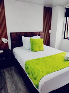 a bedroom with a large bed with a green blanket at Hotel Kristal Ferial in Bogotá