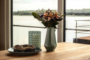 a table with a vase of flowers and a plate of food at Hausboot KonTiki - LP8 in Laasow