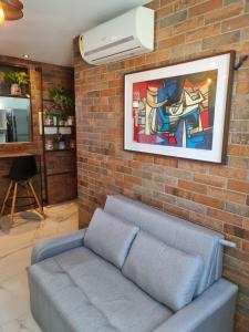 a couch against a brick wall with a painting at Apartamento em boa viagem in Recife