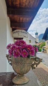 eine Vase voller lila Blumen auf einem Felsvorsprung in der Unterkunft Hotel Ferienhaus Fux in Oberammergau