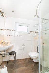 La salle de bains blanche est pourvue de toilettes et d'un lavabo. dans l'établissement K2 Bungalow - Strandhaus Königsberger Allee 8 - FERIENDOMIZIL HOLLICH, à Grömitz