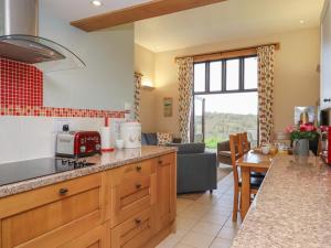 a kitchen and living room with a couch and a table at Waterland Old Barn in Holsworthy