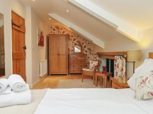 a bedroom with a bed and a dresser and a chair at Waterland Old Barn in Holsworthy