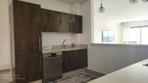 a kitchen with wooden cabinets and a stainless steel refrigerator at SURF PALACE BEACHFRONT APARTMENT Essaouira in Essaouira