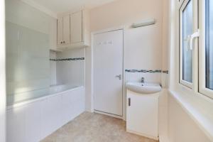 a white bathroom with a sink and a bath tub at The Elmington Estate Place - Elegant 1BDR Flat in London