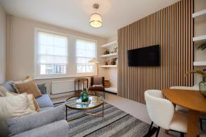 The Elmington Estate Place - Elegant 1BDR Flat في لندن: غرفة معيشة مع أريكة وتلفزيون على الحائط