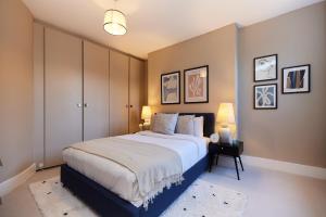 The Elmington Estate Place - Elegant 1BDR Flat في لندن: غرفة نوم بسرير كبير ومصباحين