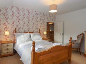 a bedroom with a bed and a chair and a wall at Waterland Farmhouse in Holsworthy