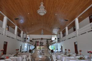 un salón de banquetes con mesas y sillas blancas y una lámpara de araña en Hotel Reina Victoria, en Guamal