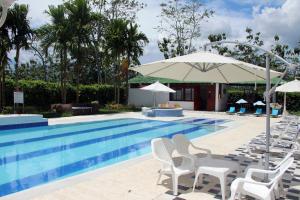 una piscina con sillas blancas y sombrilla en Hotel Reina Victoria, en Guamal