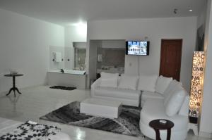 a living room with a white couch and a tv at Hotel Reina Victoria in Guamal
