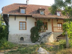 una pequeña casa blanca con techo rojo en Tisnyi 7 Guest House, en Kamianets-Podilskyi