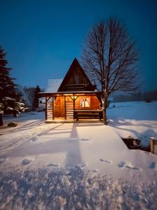 drewniany domek na śniegu z drzewem w obiekcie Casa Lidija w mieście Kupres