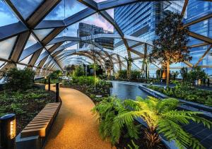 a conservatory with a bench and a pond in a building at Canary Wharf Skyline Sanctuary London in London