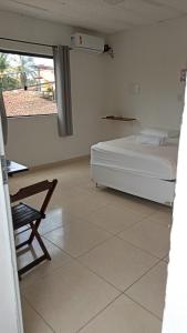 a bedroom with a bed and a chair and a window at Aluguel de suites e Apartamento in Itacaré